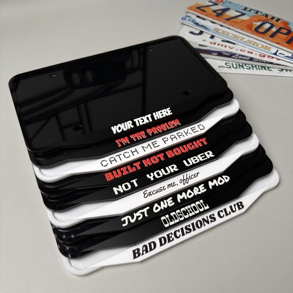 NG Frames custom acrylic license plate frames in black and white with various witty slogans stacked on a table.